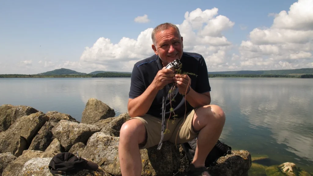 On poursuit la 2ème étape du terrain écologie ! Une personne devant un lac qui tient un matériel d'expérimentation