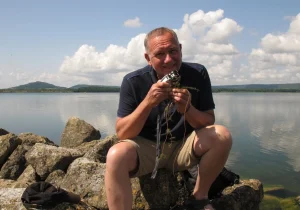 Une personne devant un lac qui tient un matériel d'expérimentation